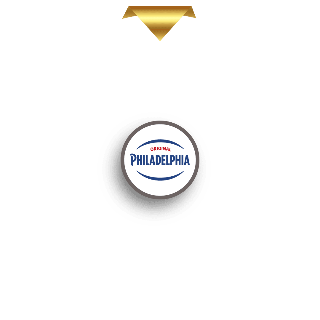 En gullpeker i form av en nedadvendt trekant er plassert over en sirkulær markør med en stilisert, glitrende gullbokstav "M" i midten. Markøren kaster en skygge og er utformet slik at den flukter med det øverste segmentet på et premiehjul (ikke vist på dette bildet).